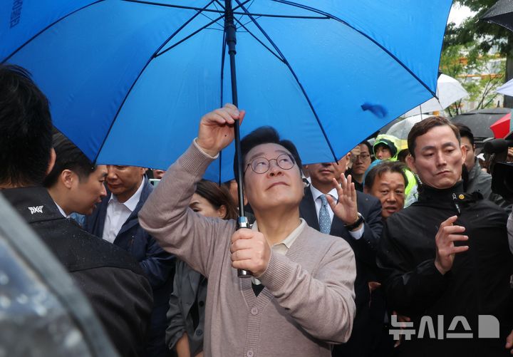 [경주=뉴시스] 조성우 기자 = 민심을 청취하는 '경청 투어'에 나선 이재명 더불어민주당 대선후보가 9일 경북 경주시 용강동 아파트단지 인근에서 비가 내리자 우산을 펼치고 있다. 2025.05.09. xconfind@newsis.com