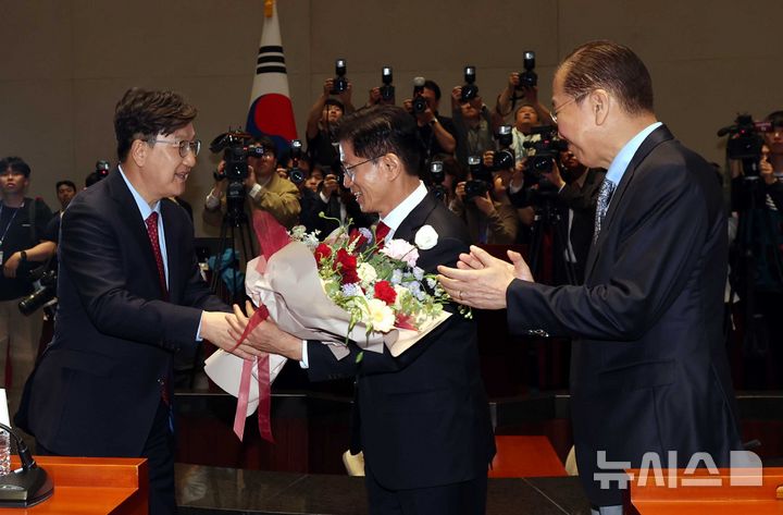 [서울=뉴시스] 조성봉 기자= 김문수 국민의힘 대선후보가 9일 서울 여의도 국회에서 열린 의원총회에서 권성동 원내대표에게 꽃다발을 받고 있다. 오른쪽은 권영세 비대위원장. 2025.05.09. suncho21@newsis.com
