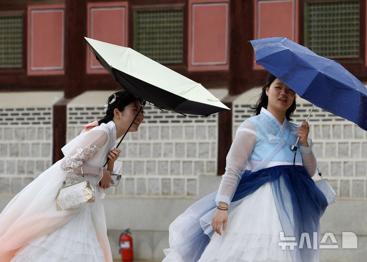 [서울=뉴시스] 김명년 기자 = 비가 내린 9일 오전 서울 종로구 경복궁에서 한복을 입은 외국인 관광객의 우산이 바람에 뒤집어지고 있다. 2025.05.09. kmn@newsis.com