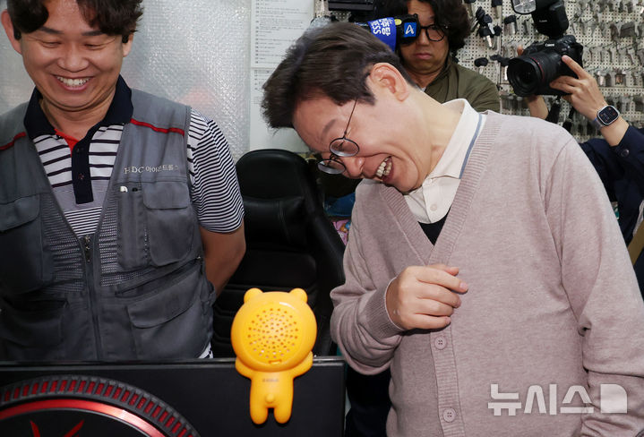 [칠곡=뉴시스] 조성우 기자 = 민심을 청취하는 '경청 투어'에 나선 이재명 더불어민주당 대선후보가 9일 경북 칠곡군 석적읍 인근 한 열쇠가게에서 한 도장가게에서 자신의 유세 모습을 실시간으로 보고 있던 상인의 모니터를 보고 활짝 웃고 있다. 2025.05.09. xconfind@newsis.com