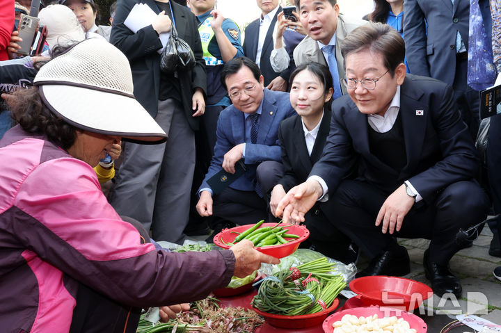 [함안=뉴시스] 조성우 기자 = 민심을 청취하는 '경청 투어'에 나선 이재명 더불어민주당 대선후보가 10일 경남 함안군 가야시장에서 한 상인에게 고추를 구매하고 있다. 2025.05.10. xconfind@newsis.com