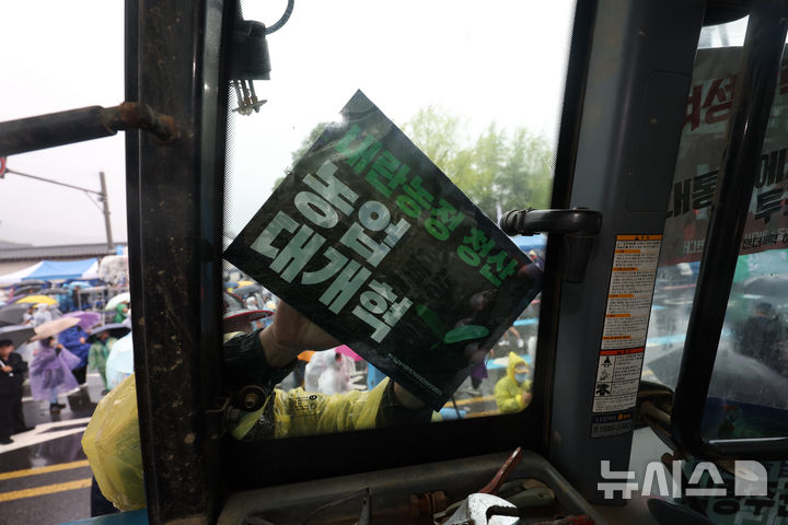 [서울=뉴시스] 김명년 기자 = 10일 오후 서울 종로구 경복궁 동십자각 인근에서 열린 내란청산·사회대개혁 비상행동 주최 사법부 정치개입 규탄 집회에서 한 농민이 도착한 전국농민회총연맹 트랙터에 피켓을 붙이고 있다. 2025.05.10. kmn@newsis.com