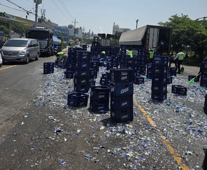 [울산=뉴시스] 박수지 기자 = 12일 오전 울산시 남구 상개삼거리에서 우회전하던 트레일러에 실린 맥주병 상자가 쏟아져 수거작업이 이뤄지고 있다. (사진=독자 제공) 2025.05.12. photo@newsis.com *재판매 및 DB 금지