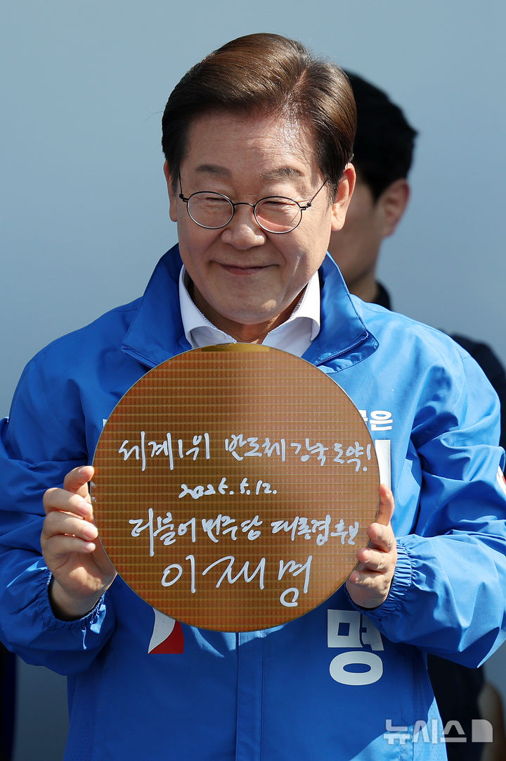 [동탄=뉴시스] 조성우 기자 = 이재명 더불어민주당 대선후보가 제21대 대통령선거 공식 선거운동이 시작된 12일 경기 화성시 동탄 센트럴파크 음악분수중앙광장에서 열린 집중유세에서 '세계선도! K-반도체!' 라고 쓴 반도체 웨이퍼를 들어 보이고 있다. 2025.05.12. xconfind@newsis.com
