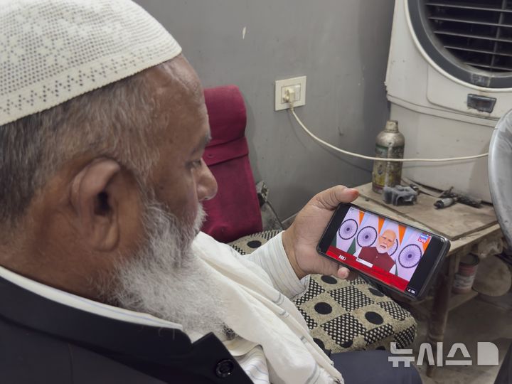 [프라야그라지=AP/뉴시스]5월12일 인도 우타르프라데시주 프라야그라지에서 한 무슬림 상인이 나렌드라 모디 총리의 대국민 담화를 휴대전화로 시청하고 있다. 인도가 모든 새로운 스마트폰에 삭제가 불가능한 국영 사이버 보안 앱을 사전 탑재하도록 명령, 개인정보 보호에 대한 우려를 부르고 있다고 BBC가 2일 보도했다. 2025.12.02.