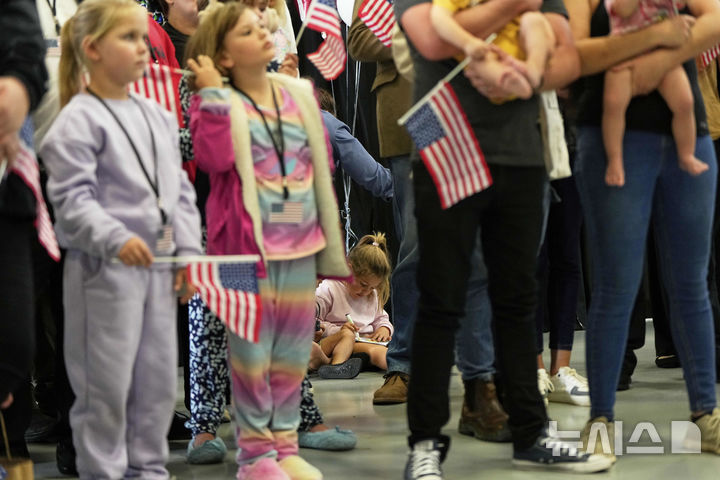 [덜레스=AP/뉴시스] 미국 국기를 든 남아프리카공화국계 아프리카너들이 12일(현지 시간) 미 버지니아주 덜레스에 있는 덜레스 국제공항에 도착하고 있다. 이날 아프리카너(16세기 이후 네덜란드 등 유럽에서 남아공으로 이주해 정착한 백인) 59명이 난민 자격으로 미국에 입국했다. 취임 뒤 사실상 난민 수용을 중단한 도널드 트럼프 행정부가 남아공 백인의 난민 지위를 인정해 미국 내 정착을 허용해 논란이 일고 있다. 2025.05.13.