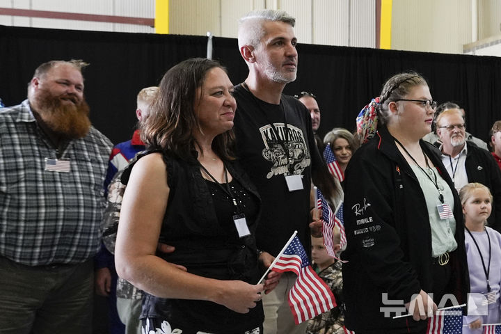 [덜레스=AP/뉴시스] 미국 국기를 든 남아프리카공화국계 아프리카너들이 12일(현지 시간) 미 버지니아주 덜레스에 있는 덜레스 국제공항에 도착하고 있다. 이날 아프리카너(16세기 이후 네덜란드 등 유럽에서 남아공으로 이주해 정착한 백인) 59명이 난민 자격으로 미국에 입국했다. 취임 뒤 사실상 난민 수용을 중단한 도널드 트럼프 행정부가 남아공 백인의 난민 지위를 인정해 미국 내 정착을 허용해 논란이 일고 있다. 2025.05.13.