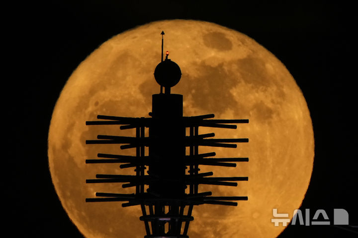 [캔자스시티=AP/뉴시스] 12일(현지 시간) 미 미주리주 캔자스시티 컨벤션 센터 옥상 조형물 뒤로 보름달이 떠오르고 있다. 2025.05.13.