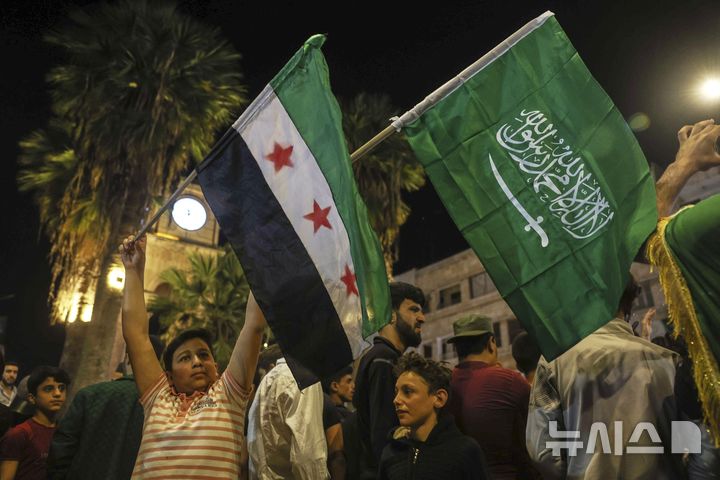 [이드리브=AP/뉴시스]지난 13일(현지 시간) 도널드 트럼프 미국 대통령의 대시리아 제재 해제 및 시리아 새 정부와의 관계 정상화 추진 발표 소식을 접한 이드리브 주민들이 거리로 나와 환호하고 있다. 2025.05.28.