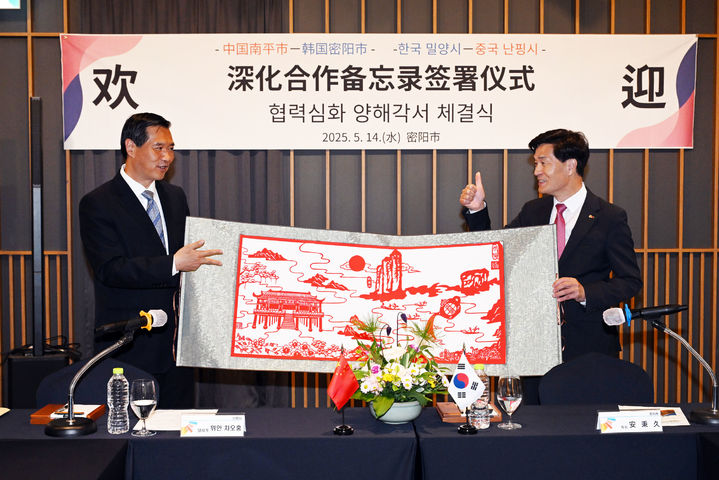 [밀양=뉴시스] 안병구(오른쪽) 시장과 차오홍 중국 난핑시 당서기가 국제자매도시 협력 심화를 위한 양해각서를 체결식에서 난핑시가 준비한 선물을 전달하고 있다. (사진=밀양시 제공) 2025.05.14. photo@newsis.com *재판매 및 DB 금지
