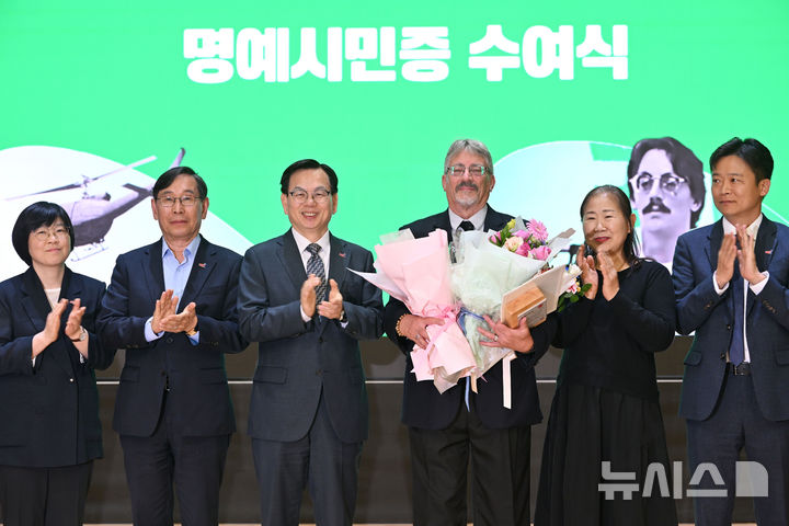 [광주=뉴시스] 이영주 기자 = '푸른 눈의 5·18 시민군' 데이비드 돌린저(David L. Dolinger·72·한국명 임대운·오른쪽 세번째)와 광주시 관계자들이 14일 오후 광주 동구 전일빌딩 245에서 열린 광주 명예시민증 수여식에서 기념사진을 촬영하고 있다. 2025.05.14. leeyj2578@newsis.com