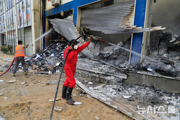 [트리폴리= AP/뉴시스] 무장 군대들 간의 충돌로 파괴된 리비아 수도 트리폴리 거리에서 5월 14일 소방대가 한 서점 화재의 잔불을 끄고 있다.  2025. 05. 15.  