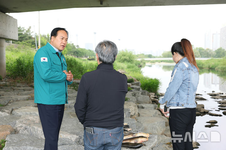 [오산=뉴시스] 이권재 시장이 오산천에 물고기가 폐사한 채 발견된 금오대교에서 관계자들과 현장점검을 벌이고 있는 모습(사진 =오산시 제공)2025.05.15.photo@nesis.com 