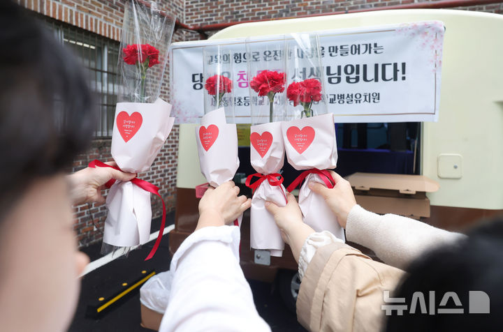 [서울=뉴시스] 홍효식 기자 = 스승의 날인 15일 서울 노원구 서울동일초등학교에서 선생님들이 학생들에게 받은 카네이션을 들고 기념촬영하고 있다. 2025.05.15. yesphoto@newsis.com