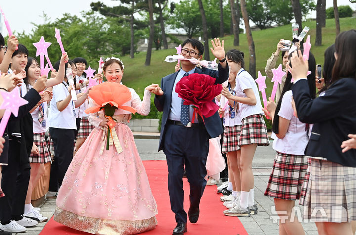 [수원=뉴시스] 김종택 기자 = 스승의날인 15일 경기 수원시 팔달구 매향중학교에서 선생님들이 레드카펫을 걸으며 학생들의 축하와 카네이션을 받고 있다. 2025.05.15. jtk@newsis.com