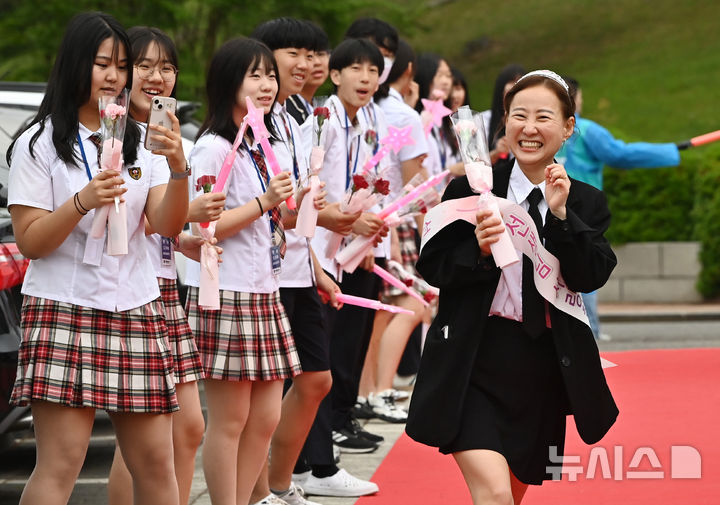 [수원=뉴시스] 김종택 기자 = 스승의날인 15일 경기 수원시 팔달구 매향중학교에서 선생님들이 레드카펫을 걸으며 학생들의 축하와 카네이션을 받고 있다. 2025.05.15. jtk@newsis.com