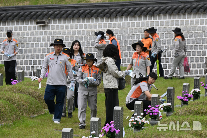 [광주=뉴시스] 박기웅 기자 = 5·18민주화운동 45주년을 3일 앞둔 15일 오전 광주 북구 운정동 국립 5·18민주묘지에서 광주 광산의용소방대 대원들이 묘비 닦기 봉사를 하고 있다. 2025.05.15. pboxer@newsis.com