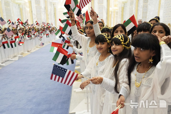 [아부다비=AP/뉴시스] 아랍에미리트(UAE) 어린이들이 15일(현지 시간) 아부다비의 카사르 알와탄 대통령궁 국빈 만찬장에서 도널드 트럼프 미국 대통령과 셰이크 무함마드 빈 자이드 알나하얀 UAE 대통령을 기다리며 양국 국기를 흔들고 있다. 2025.05.16.