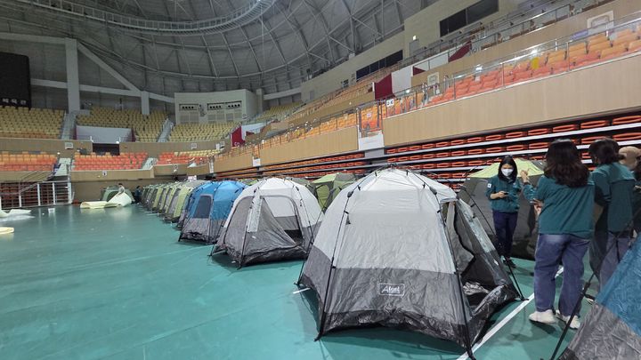[광주=뉴시스] 박기웅 기자 = 17일 오전 광주 광산구 소촌동 금호타이어 광주공장 화재 현장에서 발생한 검은 연기와 유독가스가 인근 주택가로 퍼지자 행정당국이 대피소를 마련하고 있다. 이날 광산구는 광주여자대학교 체육관에 400세대가 머무를 수 있는 텐트를 설치할 예정이다. (사진=광주 광산구 제공) 2025.05.17. photo@newsis.com *재판매 및 DB 금지