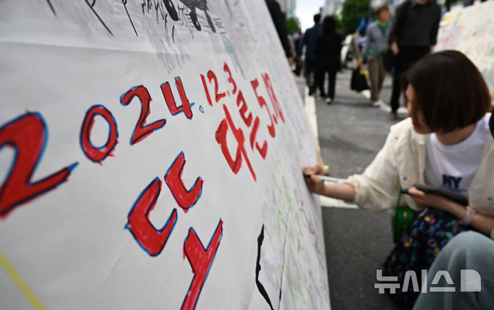 [광주=뉴시스] 김혜인 기자 = 5·18민주화운동 45주년 전야제 부스가 마련된 17일 오후 광주 동구 금남로에서 한 시민이 자유 게시판에 오월정신을 되새기는 적고 있다. 2025.05.17. hyein0342@newsis.com