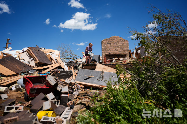 [런던( 미 켄터키주)=AP/뉴시스] 미 켄터키주의 주민 헤일리 앨런이 토네이도로 완파된 집터에서 5월 17일 가족 사진을 가까스로 구해내 옮기고 있다. 2025. 05. 18.&nbsp; 