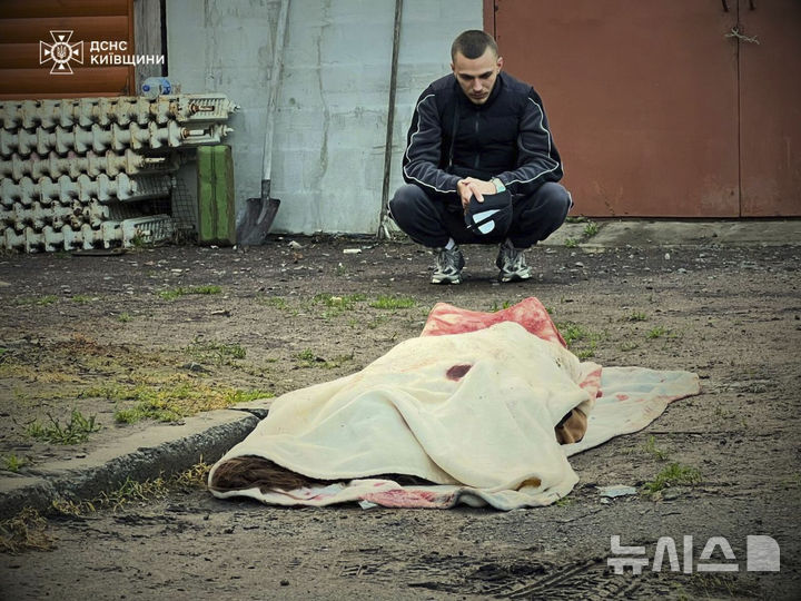 [키이우=AP/뉴시스]지난 18일(현지시각) 러시아의 우크라이나 수도 공격으로 숨진 사람을 한 남성이 지켜보고 있다. 러시아는 23일밤 24일 새벽에 걸쳐 다시 키이우를 대대적으로 공습했다. 2025.5.24. 