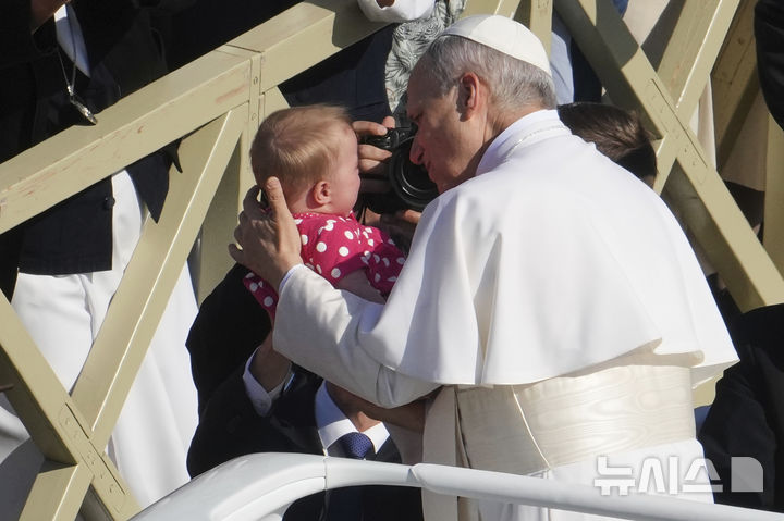 [바티칸=AP/뉴시스] 교황 레오 14세가 18일(현지 시간) 바티칸 성 베드로 광장에서 열린 즉위 미사에 참석하며 아이에게 입을 맞추고 있다. 2025.05.19.