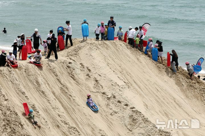 [부산=뉴시스] 하경민 기자 = '2025년 해운대 모래축제'가 열린 18일 부산 해운대구 해운대해수욕장에서 시민과 관광객들이 샌드보드를 즐기고 있다.  오는 19일까지 열리는 이번 축제에는 14명의 해외 모래 작가가 제작한 총 20여 개의 모래작품을 선보이며, 축제가 끝난 이후에도 6월8일까지 모래작품을 전시한다. 2025.05.18. yulnetphoto@newsis.com