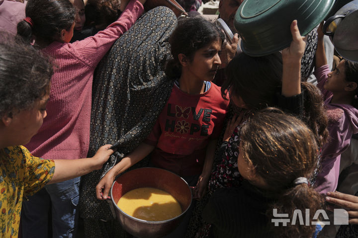 [자발리아=AP/뉴시스] 19일(현지 시간) 가자지구 북부 자발리아의 급식소에 구호 음식을 받으려는 팔레스타인 주민들이 몰려들고 있다. 이스라엘은 지난 10주간 가자지구 내 구호물자 반입을 전면 차단해 왔던 봉쇄를 완화하고 기본 식량 반입을 허용하기로 했다. 2025.05.20.