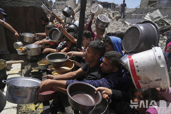 [자발리아=AP/뉴시스] 19일(현지 시간) 가자지구 북부 자발리아의 급식소에 구호 음식을 받으려는 팔레스타인 주민들이 몰려들고 있다. 이스라엘은 지난 10주간 가자지구 내 구호물자 반입을 전면 차단해 왔던 봉쇄를 완화하고 기본 식량 반입을 허용하기로 했다. 2025.05.20.