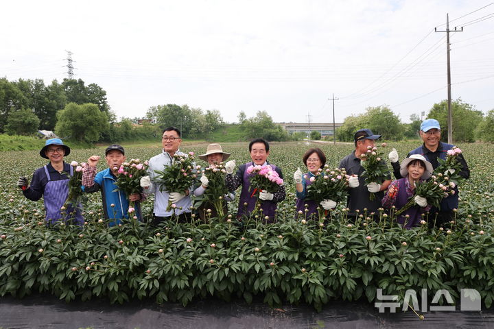 [진천=뉴시스] 19일 충북 진천군 이월면 신월리 일원에서 절화(切花)인 '작약' 수확 시작을 알리며 송기섭(왼쪽 다섯 번째) 군수와 월촌마을 주민들이 기념촬영을 하고 있다. (사진=진천군 제공) 2025.05.19. photo@newsis.com
