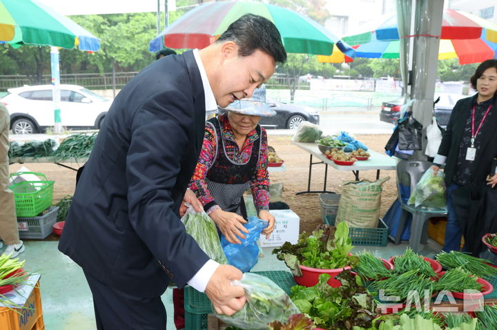 [의왕=뉴시스] 농산물 직거래 장터인 '행복한 농부 시장' 개장에 참석한 김성제 시장이 판매 품목을 둘러보고 있다. (사진=의왕시 제공).2025.05.19.photo@newsis.com