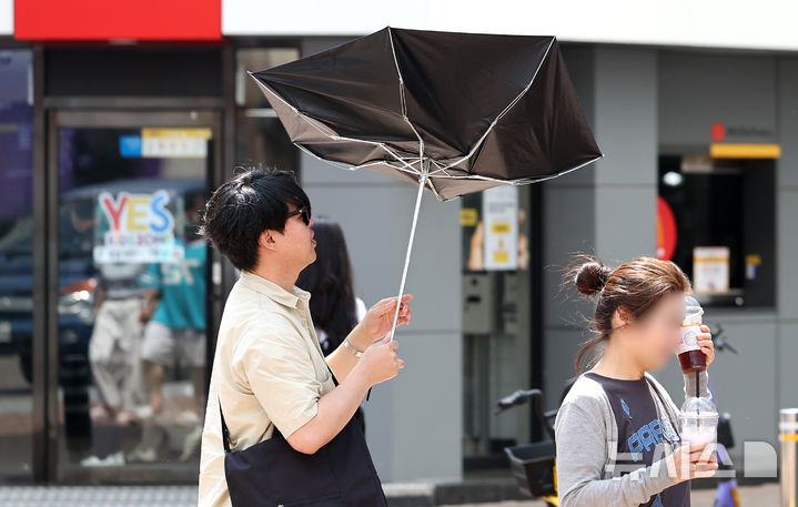 [대구=뉴시스] 이무열 기자 = 대구 낮 최고기온이 28도까지 오르며 초여름 날씨를 보인 19일 대구 중구 동성로에서 한 시민이 바람에 뒤집어진 양산으로 햇빛을 가린 채 길을 걷고 있다. 2025.05.19. lmy@newsis.com