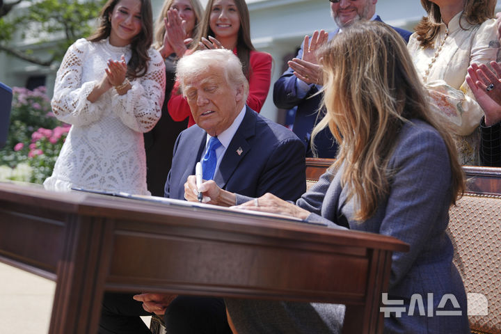 [워싱턴=AP/뉴시스] 도널드 트럼프 미국 대통령이 19일(현지 시간) 백악관 로즈가든에서 열린 이른바 '리벤지 포르노(보복성 음란물)'와 '딥페이크(AI 이용 합성 사진) 음란물' 피해자들에 대한 보호를 강화하는 법안 서명식에 참석해 멜라니아 트럼프 여사의 서명 모습을 지켜보고 있다. 이 법안은 인공지능(AI) 기반의 '딥페이크' 이미지까지 포함해 온라인에서의 사생활 침해에 강력히 대응하는 내용을 담고 있다. 2025.05.20.