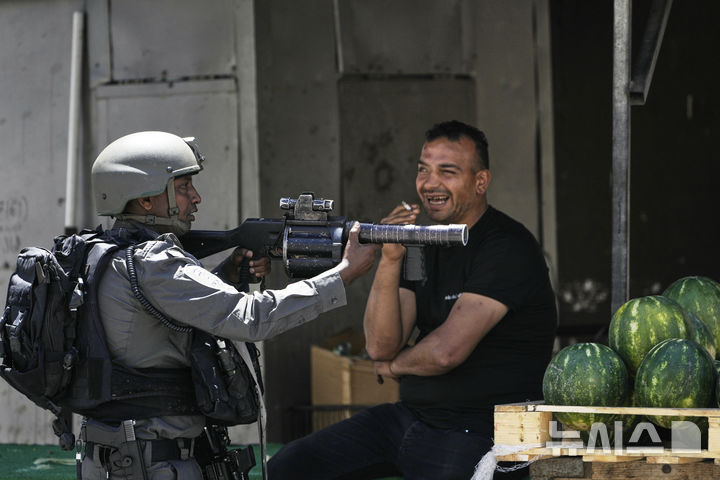 [나블루스=AP/뉴시스]지난 5월 21일 요르단강 서안지구 나블루스 인근 아스카르 난민캠프에서 이스라엘군이 기습 작전 중 수박 노점 옆에서 총을 겨누고 있다. 서안지구에서는 이스라엘군과 이스라엘정착촌민이 6월 19일 또 팔 주민들에게 총격을 가해 수리프에서 9명의 사상자가 발생했다. 2025. 06.20. 