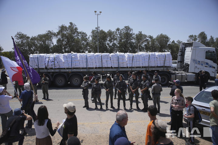 [AP/뉴시스] 21일 가자 남동단의 이스라엘 운영 켈렘 샬롬 통과지의 이스라엘 쪽 모습으로 구호물자를 실을 트럭이 가자 안으로 들어가지 못하도록 이스라엘 우파 단체들이 시위하는 것을 이스라엘 군경찰이 지켜보고 있다