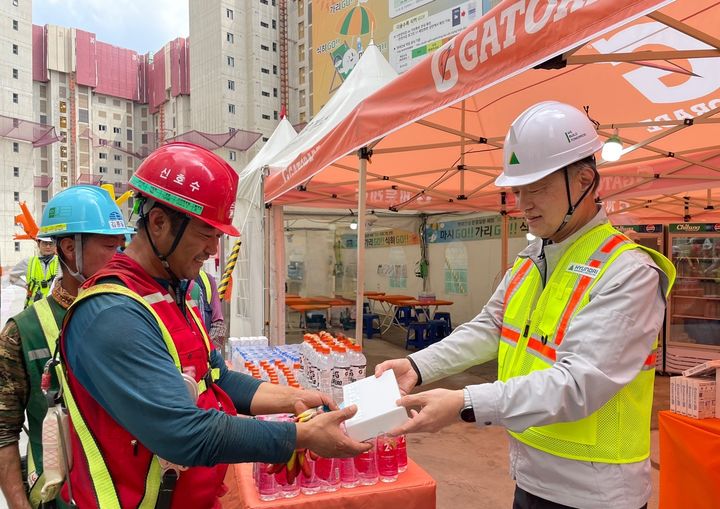 [서울=뉴시스] 현대건설 CSO 황준하 전무가 지난 21일 근로자에게 수분 보충과 탈수 예방을 위한 이온음료와 쿨링스프레이를 직접 전달하고, 근로자들의 노고를 격려하는 모습. 2025.05.22. (사진=현대건설 제공) photo@newsis.com *재판매 및 DB 금지