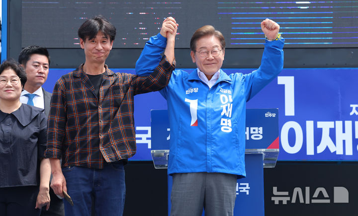 [제주=뉴시스] 우장호 기자 = 이재명 더불어민주당 대선 후보가 22일 오전 제주시 일도일동 동문로터리에서 열린 유세에서 배우 박혁권와 함께 지지자들에게 인사를 하고 있다. 2025.05.22. woo1223@newsis.com