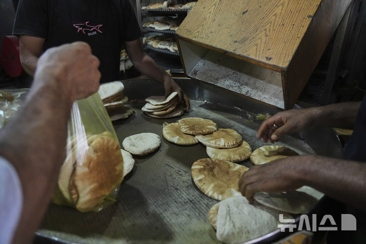 [데이르알발라=AP/뉴시스] 22일(현지 시간) 이스라엘이 일부 구호물자의 가자지구 반입을 허용함에 따라 세계식량계획(WFP)이 밀가루를 들여오자, 데이르알발라에서 팔레스타인 주민들이 빵을 굽고 있다. 2025.05.23.