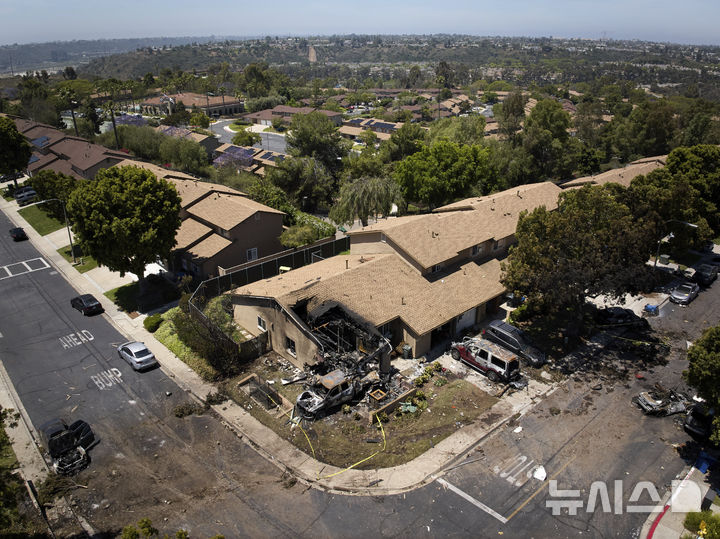 Debris covers the ground after a small plane crashed into a San Diego neighborhood, setting homes and cars on fire and forcing evacuations early Thursday, May 22, 2025. (AP Photo/William Liang)