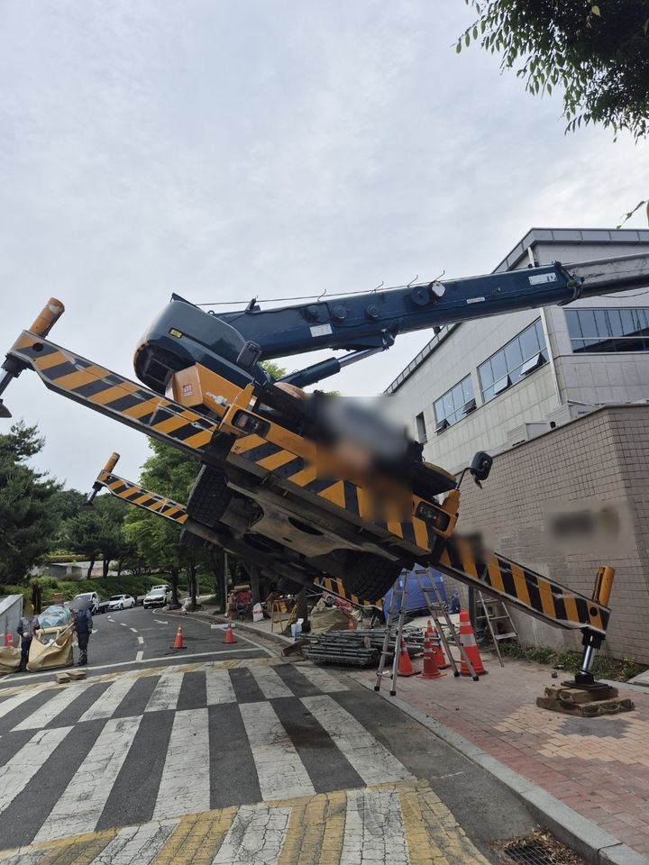 [부산=뉴시스] 23일 오후 부산 기장군의 한 증축공사 현장에서 50t 크레인이 건물에 시스템 에어콘 실외기를 올리는 작업을 하던 중 중심을 잃고 옆으로 넘어지는 사고가 발생했다. (사진=부산경찰청 제공) 2025.05.23. photo@newsis.com *재판매 및 DB 금지