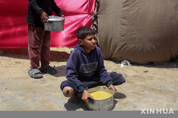 [가자시티=신화/뉴시스] 22일(현지 시간) 가자지구 가자시티의 식량 배급소에서 팔레스타인 어린이들이 무료로 받은 음식을 옮기고 있다. 2025.05.23.