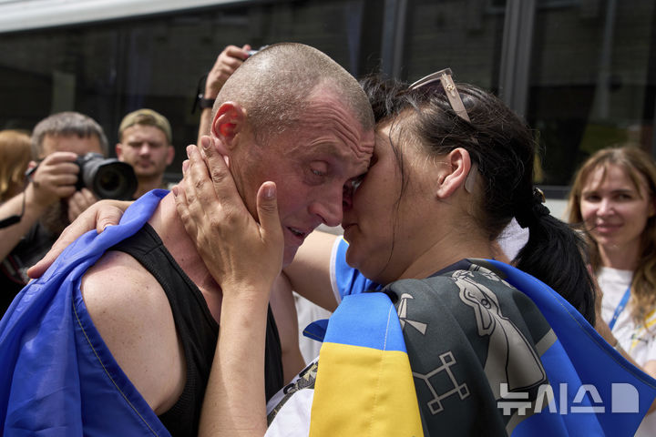 [AP/뉴시스] 우크라-러시아 간 전쟁포로 추가석방이 이뤄진 25일 우크라 체르니히우 접경지서 한 포로와 아내가 상봉하고 있다. 부부 모두 노랑과 파랑의 우크라 국기를 몸에 두르고 있다.