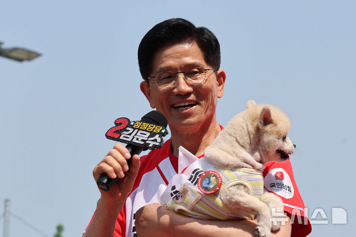 [보령=뉴시스] 권창회 기자 = 김문수 국민의힘 대선 후보가 25일 오전 충남 보령군 대천역 광장에서 열린 집중유세에서 태극기를 두른 강아지를 안고 있다. 2025.05.25. kch0523@newsis.com