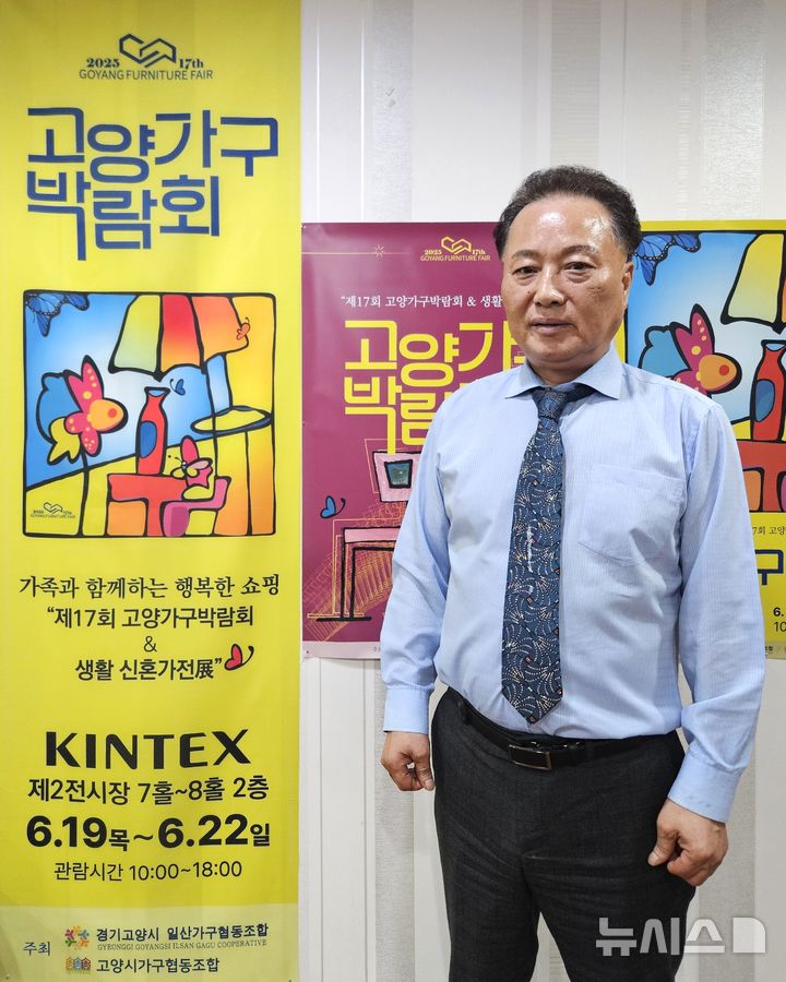 [인천=뉴시스] 이루비 기자 = 강점희 경기고양시일산가구협동조합 이사장이 조합 사무실에 게시된 '제17회 고양가구박람회' 포스터 앞에서 기념 촬영하고 있다. 2025.05.26. ruby@newsis.com