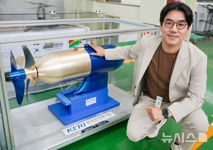 [창원=뉴시스]한국전기연구원(KERI) 전동력연구센터 홍도관 박사와 홍 박사 연구팀이 세계 최초로 개발한 '50kW급 비접촉 마그네틱 기어 적용 상반회전 프로펠러' 옆에서 포즈를 취하고 있다.(사진=KERI 제공) 2025.05.27. photo@newsis.com