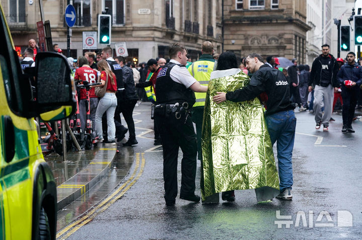 [리버풀=AP/뉴시스] 26일(현지 시간) 영국 리버풀 워터 스트리트에서 열린 리버풀FC의 프리미어리그(EPL) 우승 축하 퍼레이드 현장에서 군중들 사이로 차량이 돌진하는 사고가 발생해 소방대원과 경찰이 부상자를 이송하고 있다. 2025.05.27.