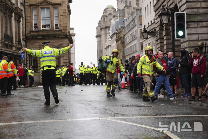 [리버풀=AP/뉴시스] 26일(현지 시간) 영국 리버풀 워터 스트리트에서 열린 리버풀FC의 프리미어리그(EPL) 우승 축하 퍼레이드 현장에서 군중들 사이로 차량이 돌진하는 사고가 발생해 소방대원과 경찰이 부상자를 이송하고 있다. 2025.05.27.