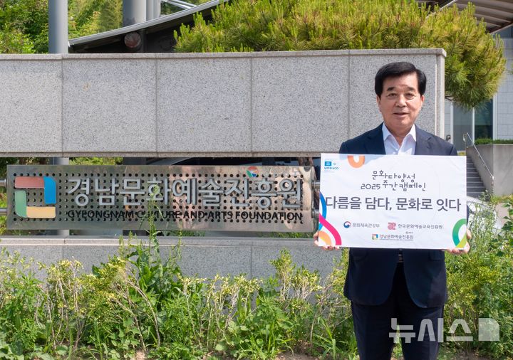 [창원=뉴시스]김종부 경남문화예술진흥원장이 27일 진흥원 입구에서 문화다양성 2025 주간 캠페인 동참 피켓을 들고 포즈를 취하고 있다.(사진=경남문화예술진흥원 제공) 2025.05.27. photo@newsis.com