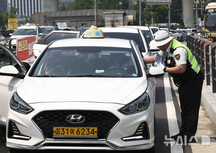 [서울=뉴시스] 김근수 기자 = 27일 서울 중구 서울역 택시승강장에서 서울경찰청 소속 경찰관들이 택시 운전사에게 ‘택시 뒷좌석 안전띠’ 착용 일상화 캠페인을 하고 있다. 2025.05.27. ks@newsis.com